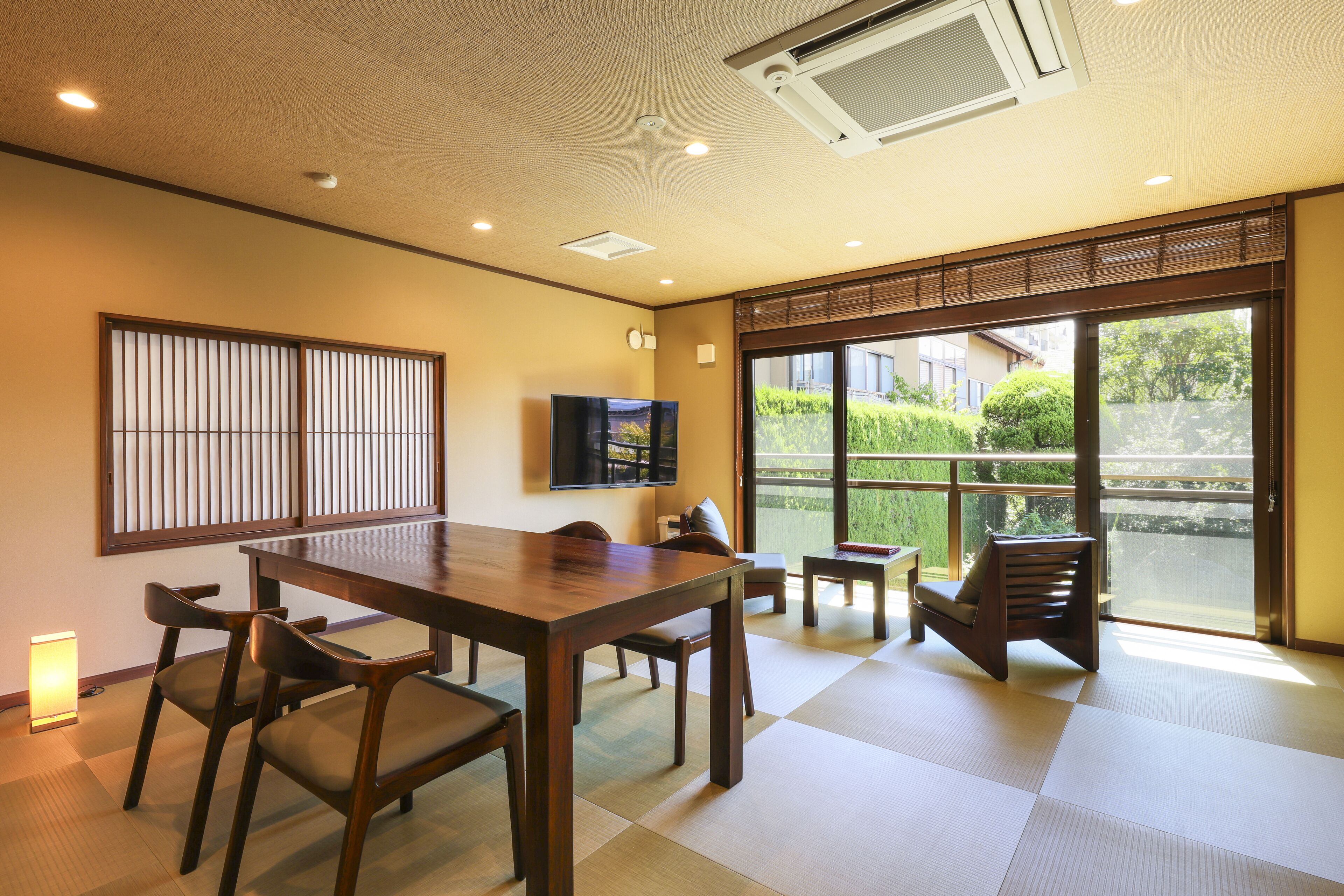 A traditional Japanese-style room with tatami flooring, a wooden table, and chairs.