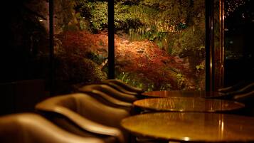 A dimly lit interior with a view of a moss-covered rock garden and autumn foliage.