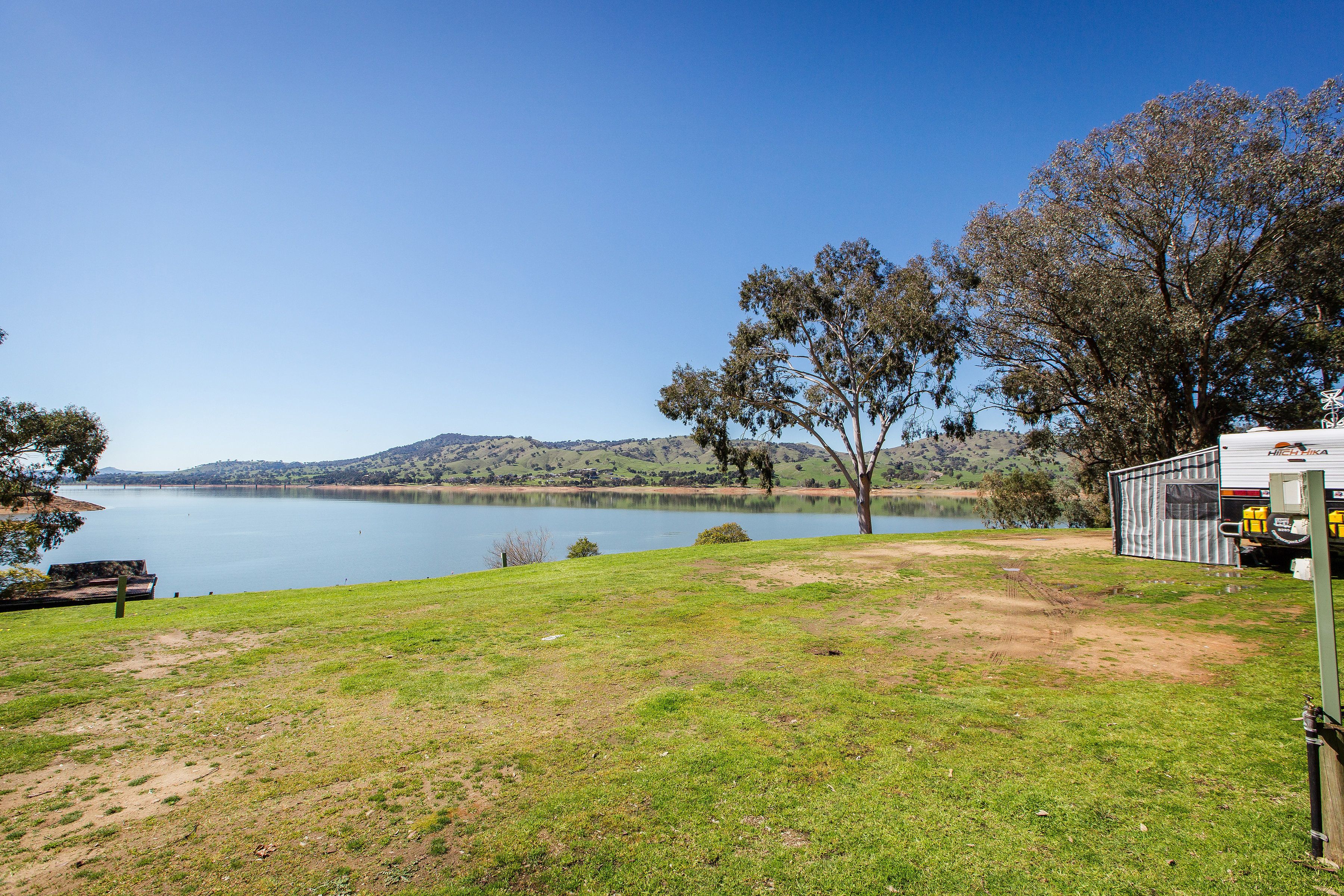 A campsite with a lake view, a trailer, and a picnic table.