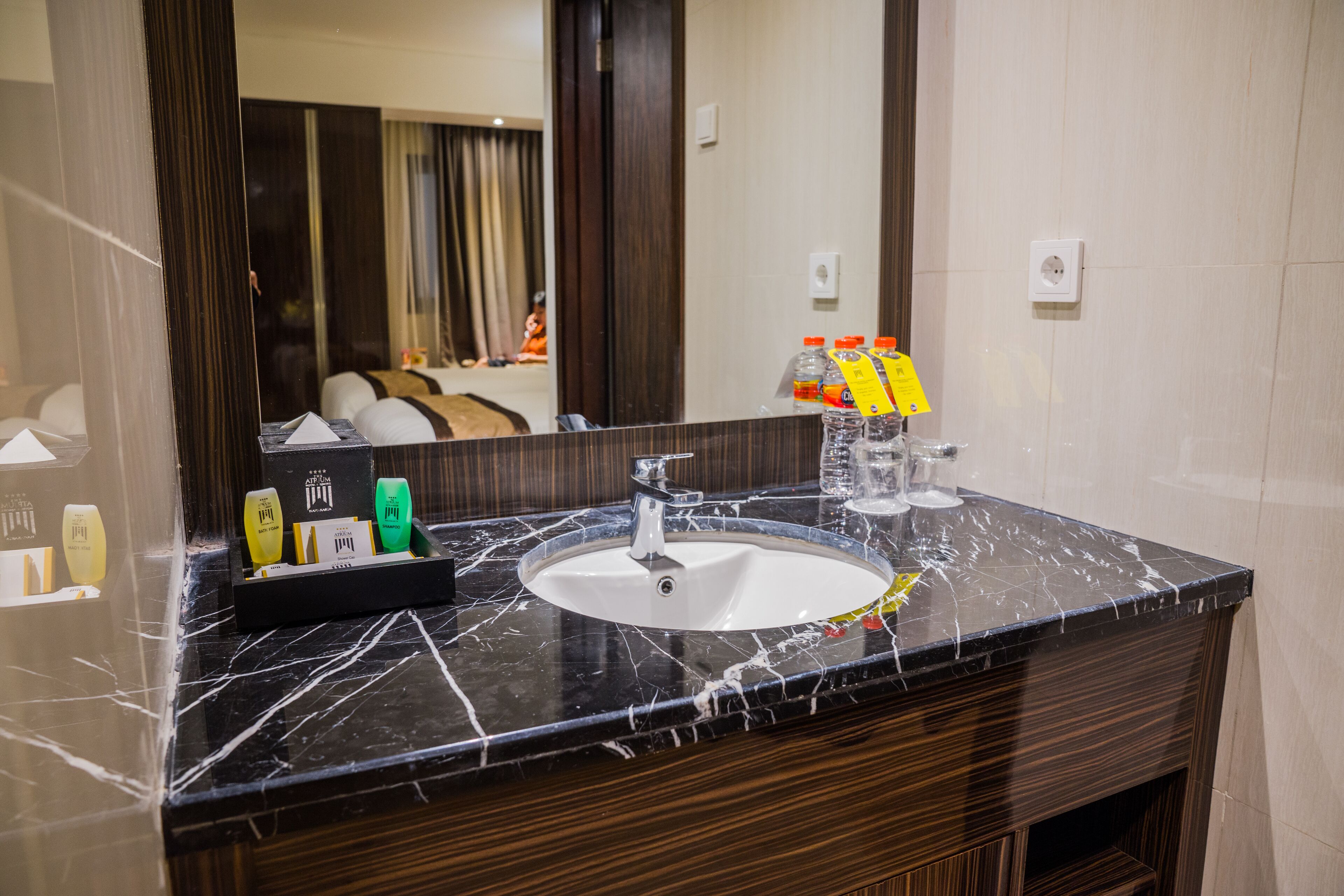A bathroom with a marble sink, a mirror, toiletries, and a towel rack.