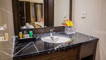 A bathroom with a marble sink, a mirror, toiletries, and a towel rack.
