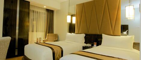 Habitación de hotel con dos camas, un espejo grande y una silla.