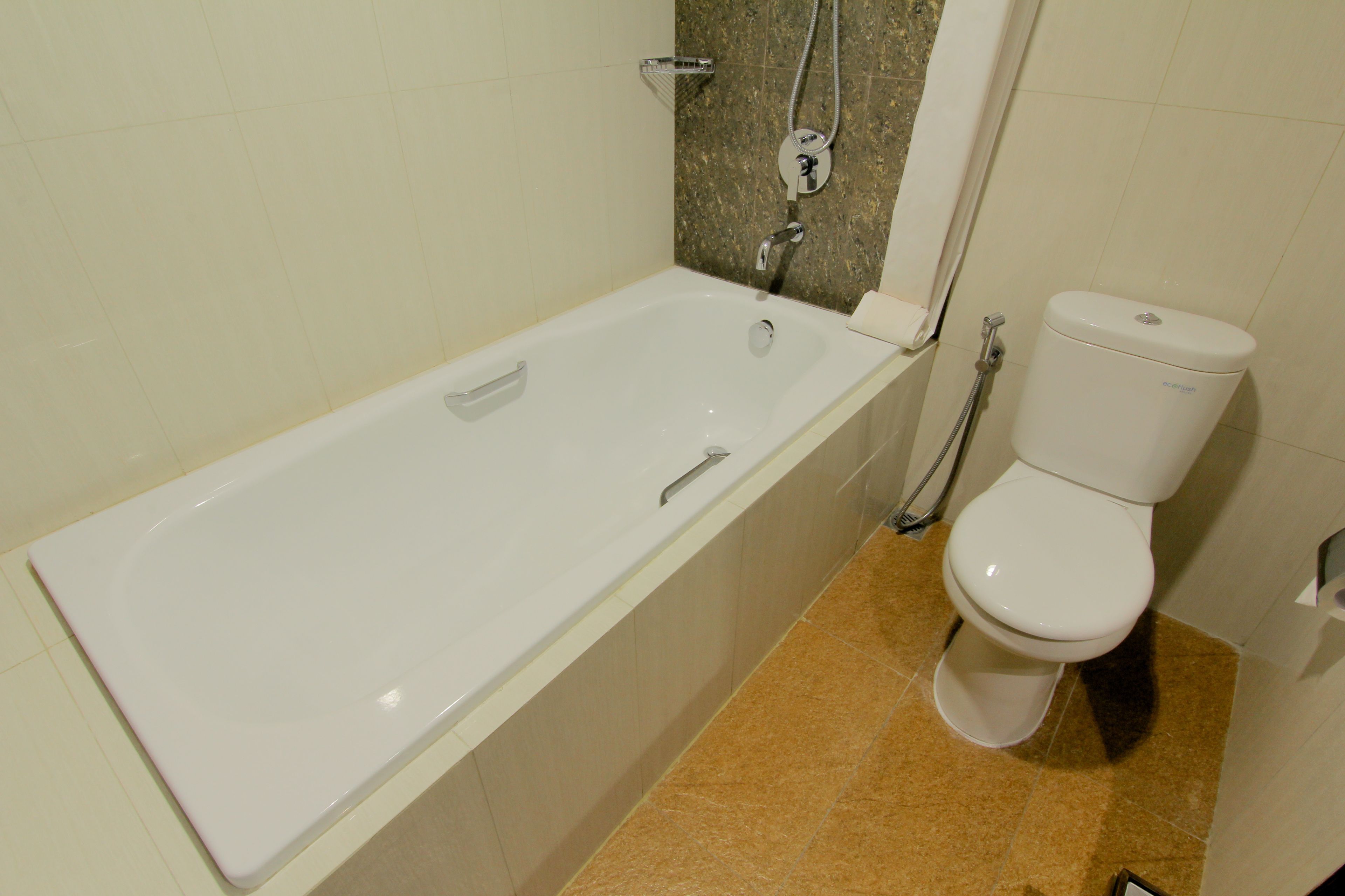 Een badkamer met een witte badkuip, toilet en een douche.