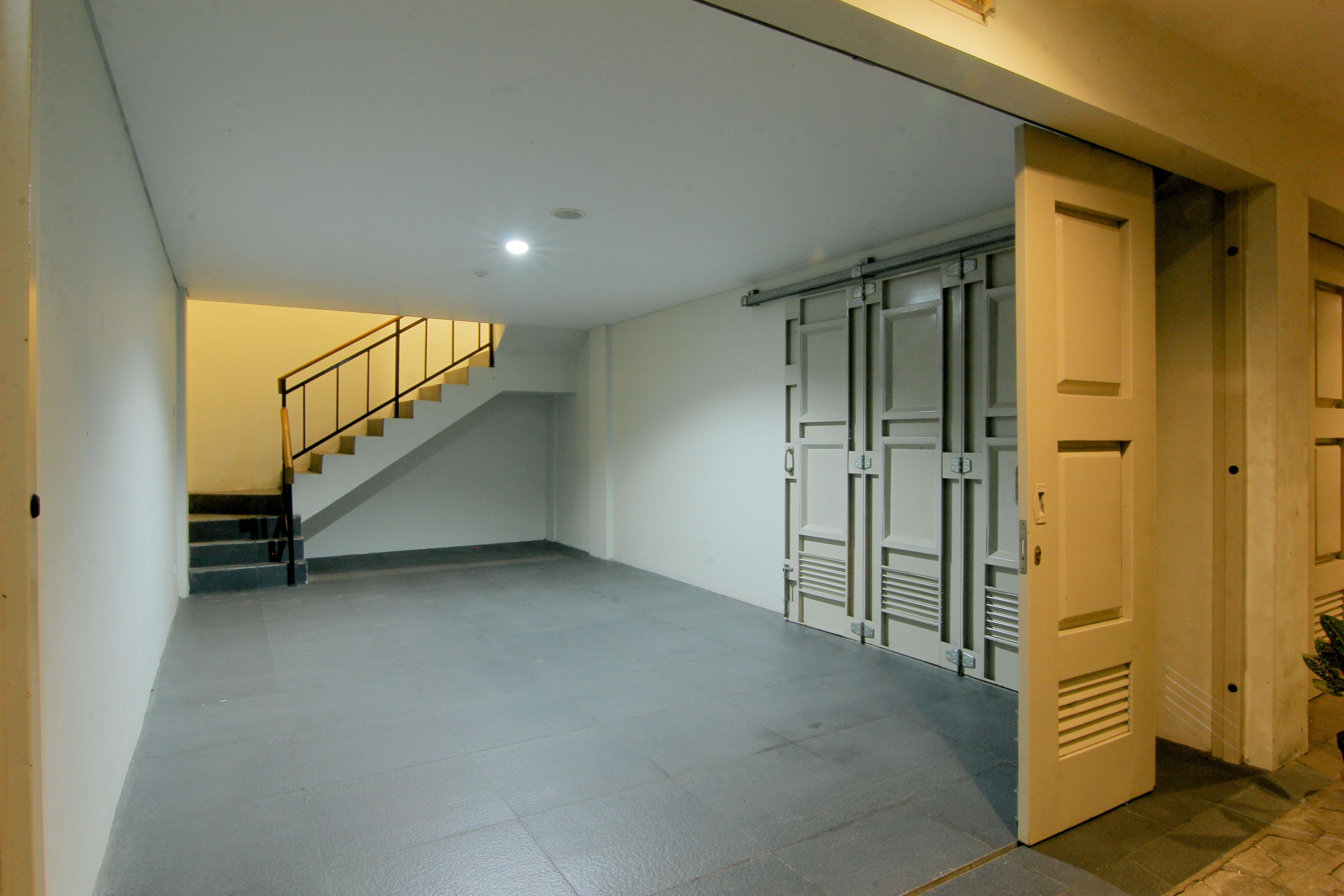 A spacious, well-lit hallway with a staircase leading to an upper floor. A set of metal lockers is visible on the right side.