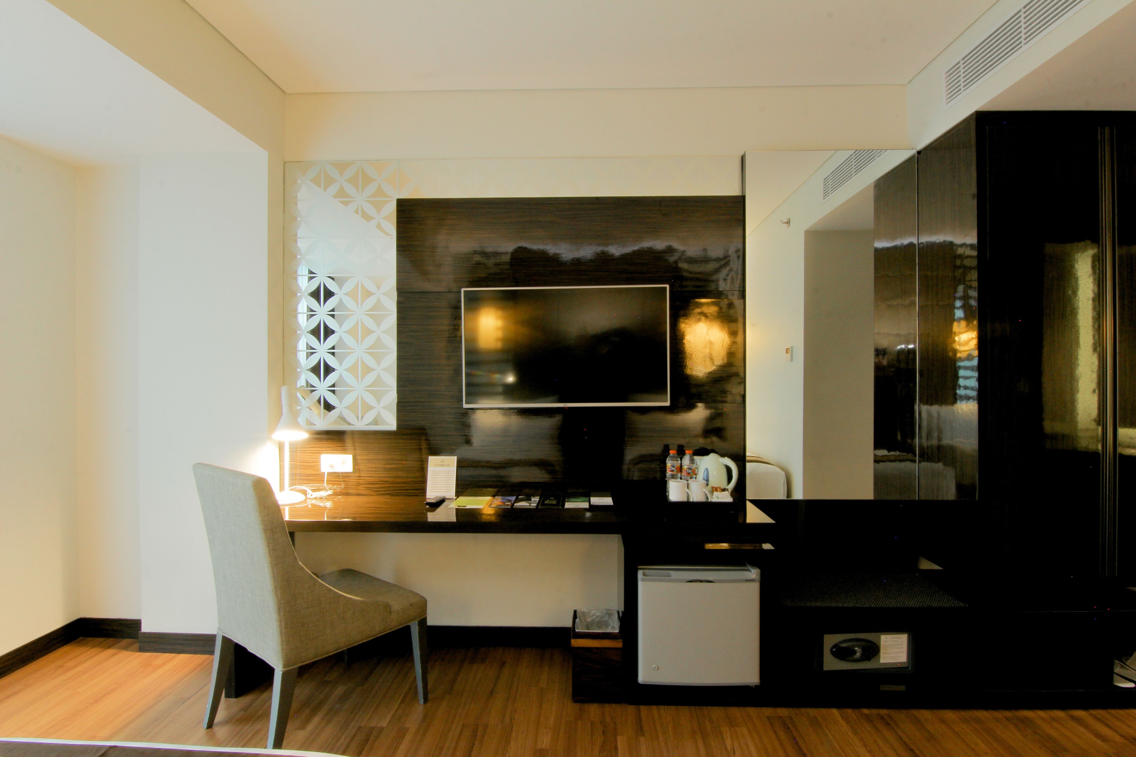 Een compacte hotelkamer met een kitchenette, een flatscreen televisie, een kleine koelkast en een zithoek met een fauteuil.
