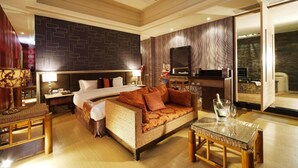 Una habitación de hotel con una cama grande, un sofá, una mesa de comedor y un televisor.