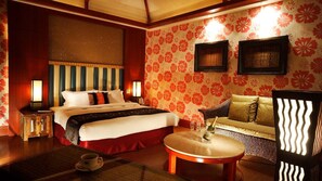A hotel room with a large bed, a sofa, a small table, and a decorative wall with floral patterns. - Seasons Boutique Motel (Kaohsiung)