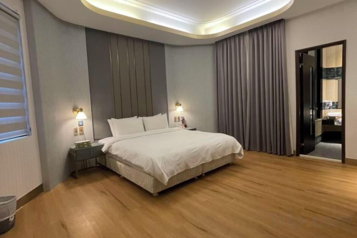 Ein modernes Hotelzimmer mit einem großen Bett, Nachttischen und Blick ins Badezimmer.