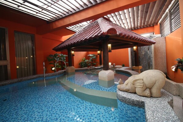 An indoor swimming pool with a tiled floor, a wooden gazebo, and a stone elephant sculpture. - Seasons Boutique Motel (Kaohsiung)