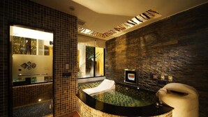 Un baño moderno con pared de piedra, ducha con cerramiento de vidrio y una bañera grande.