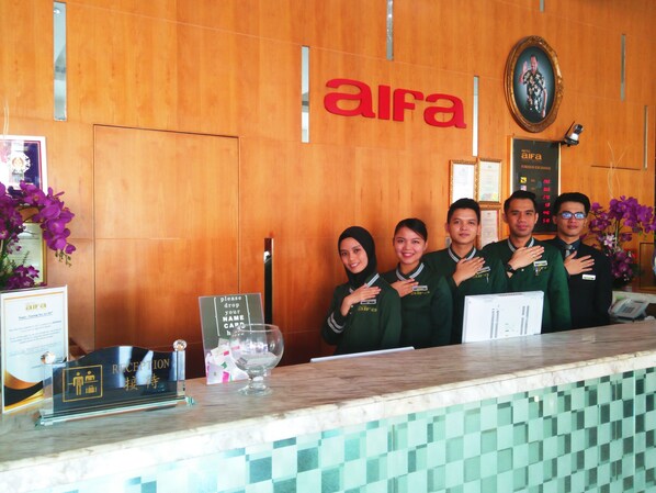 A hotel reception area with a wooden wall and a reception desk.