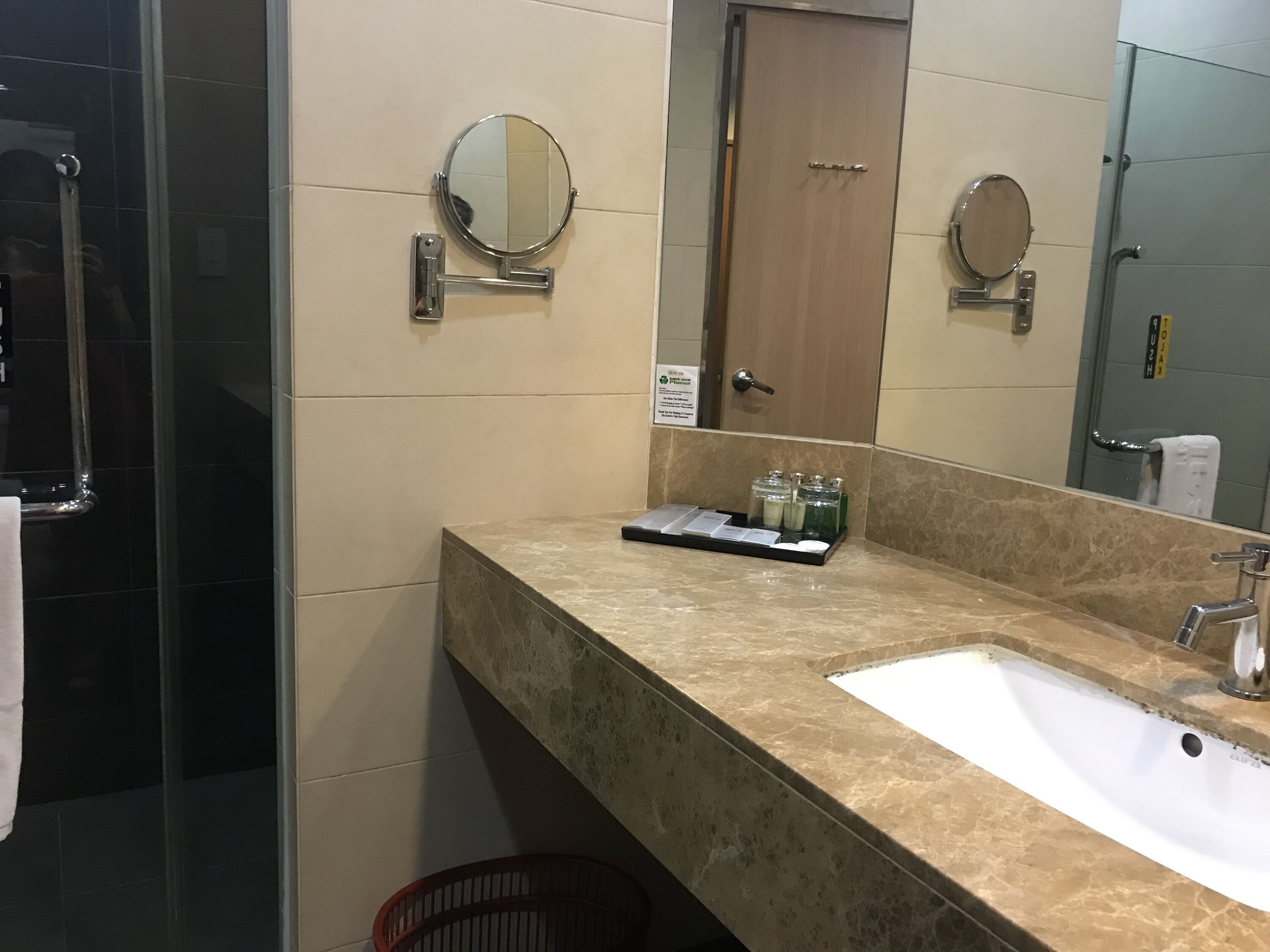 A bathroom with a marble sink, a mirror, and a towel rack.