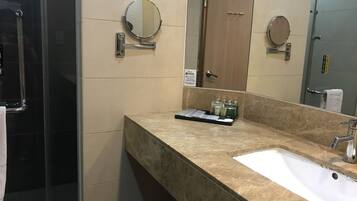 A bathroom with a marble sink, a mirror, and a towel rack.