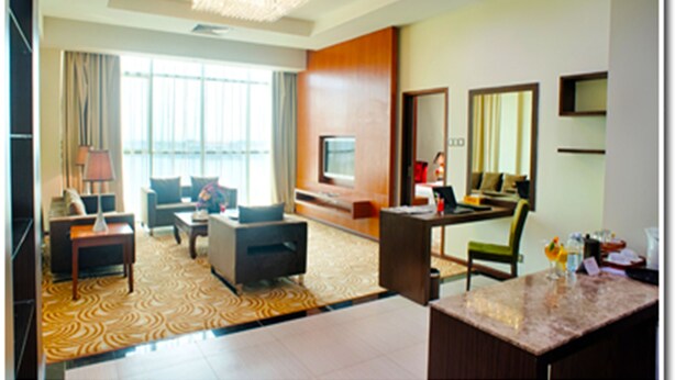 A hotel room with a large window, a sofa, a coffee table, a TV, and a desk with a chair. - Hotel Aifa (Labuan)