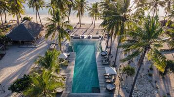 Un resort con piscina, sillas de descanso y palmeras.
