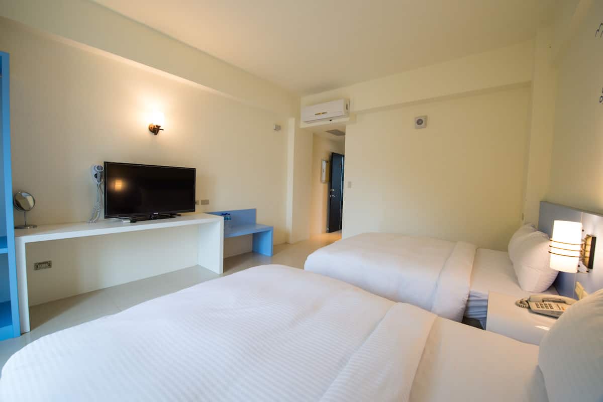 A hotel room with two beds, a TV, a desk, and a phone.