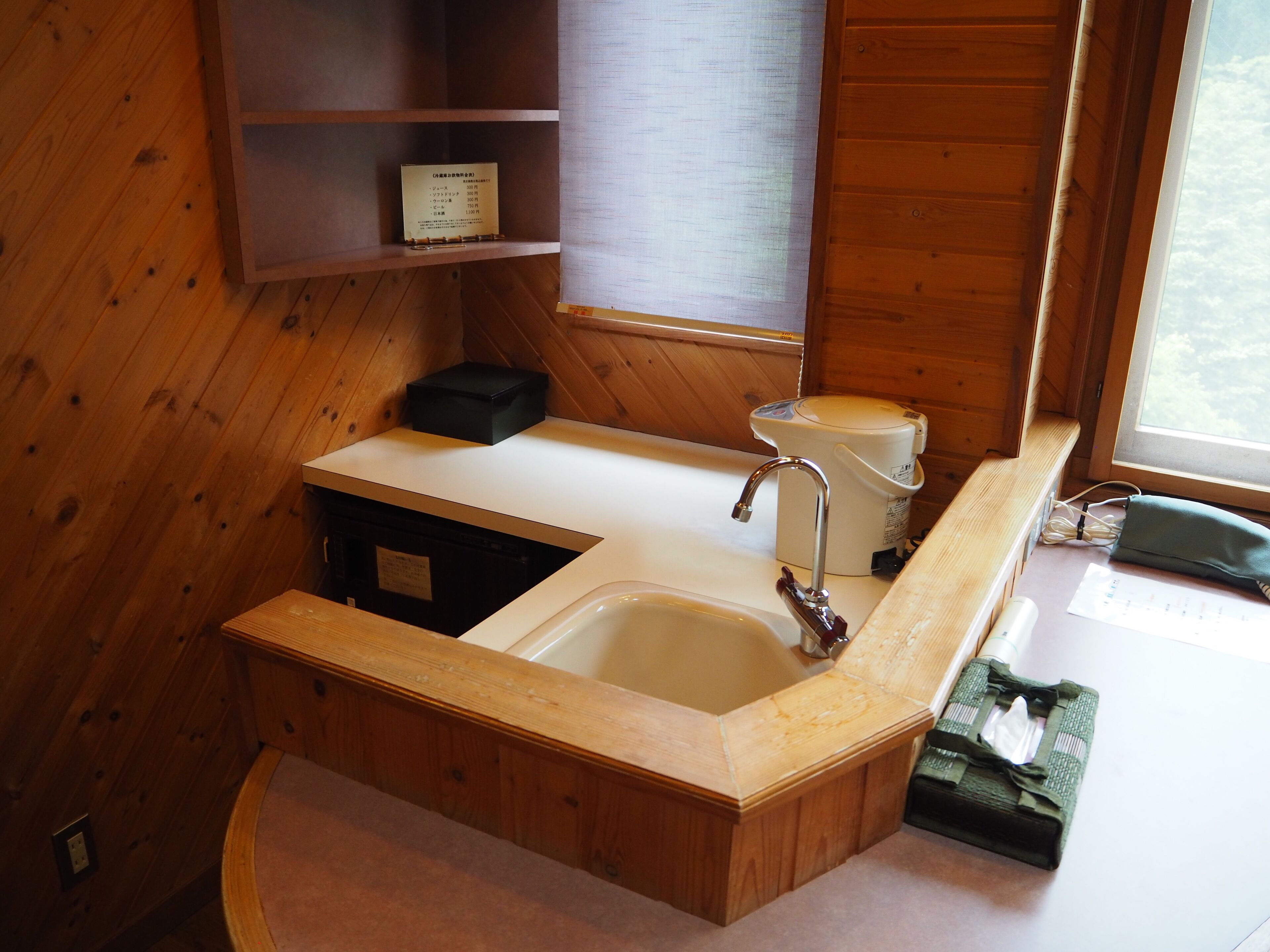 Une salle de bain rustique, aménagée dans une cabane en bois, avec un lavabo, des toilettes et une fenêtre.