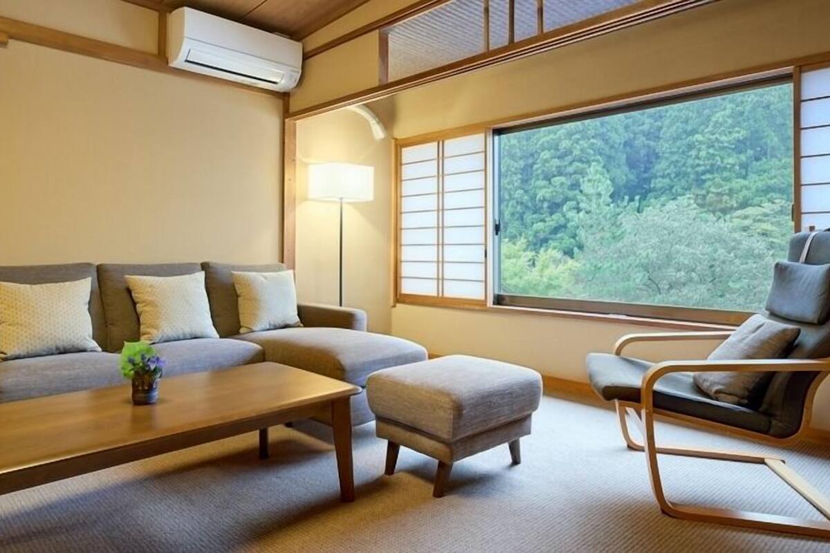 A room with a sofa, ottoman, chair, and a table.
