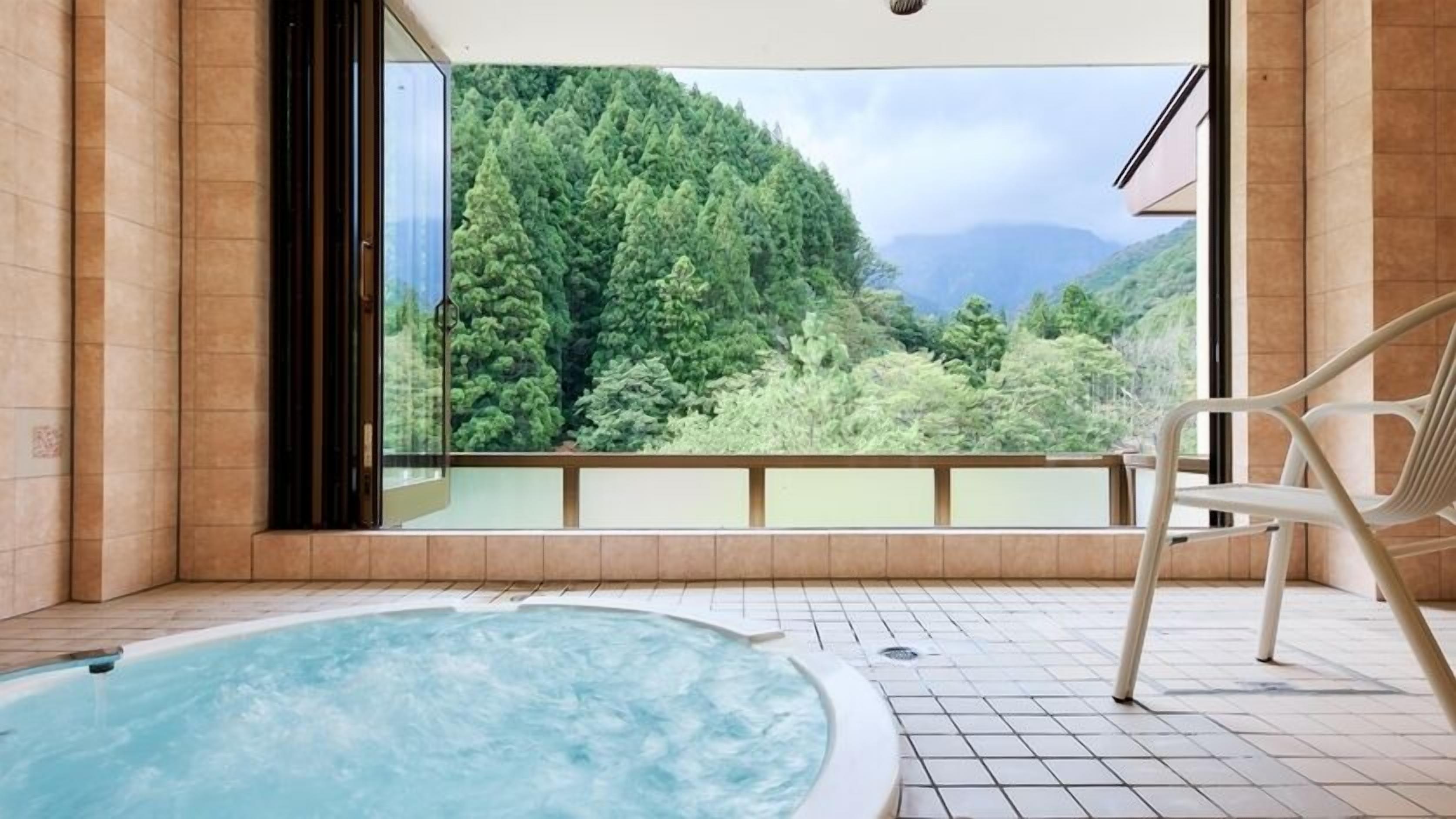 A hot tub with a view of a forested mountain.