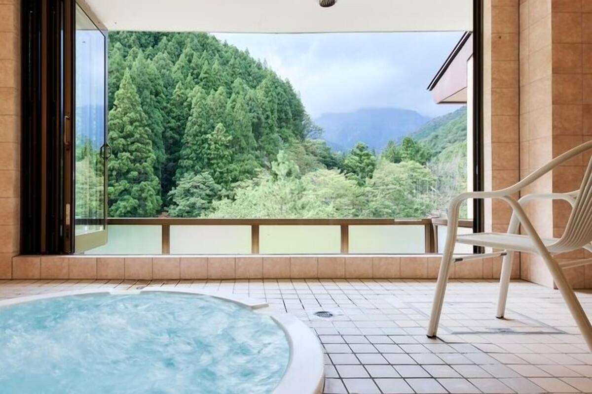 A hot tub with a view of a forested mountain.