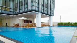 Un hotel moderno con una amplia piscina cubierta, tumbonas y una zona de estar techada.