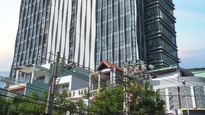 Un moderno edificio de gran altura con un diseño vertical distintivo y fachada de vidrio reflectante.