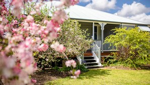 A house with a porch, surrounded by blooming trees and a clear sky. - Apple Blossom Cottage (Stanthorpe)