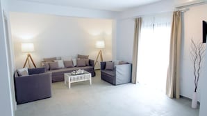 A modern living room with a sofa set, a coffee table, and a lamp. - Stavros Beach Hotel (Volvi)