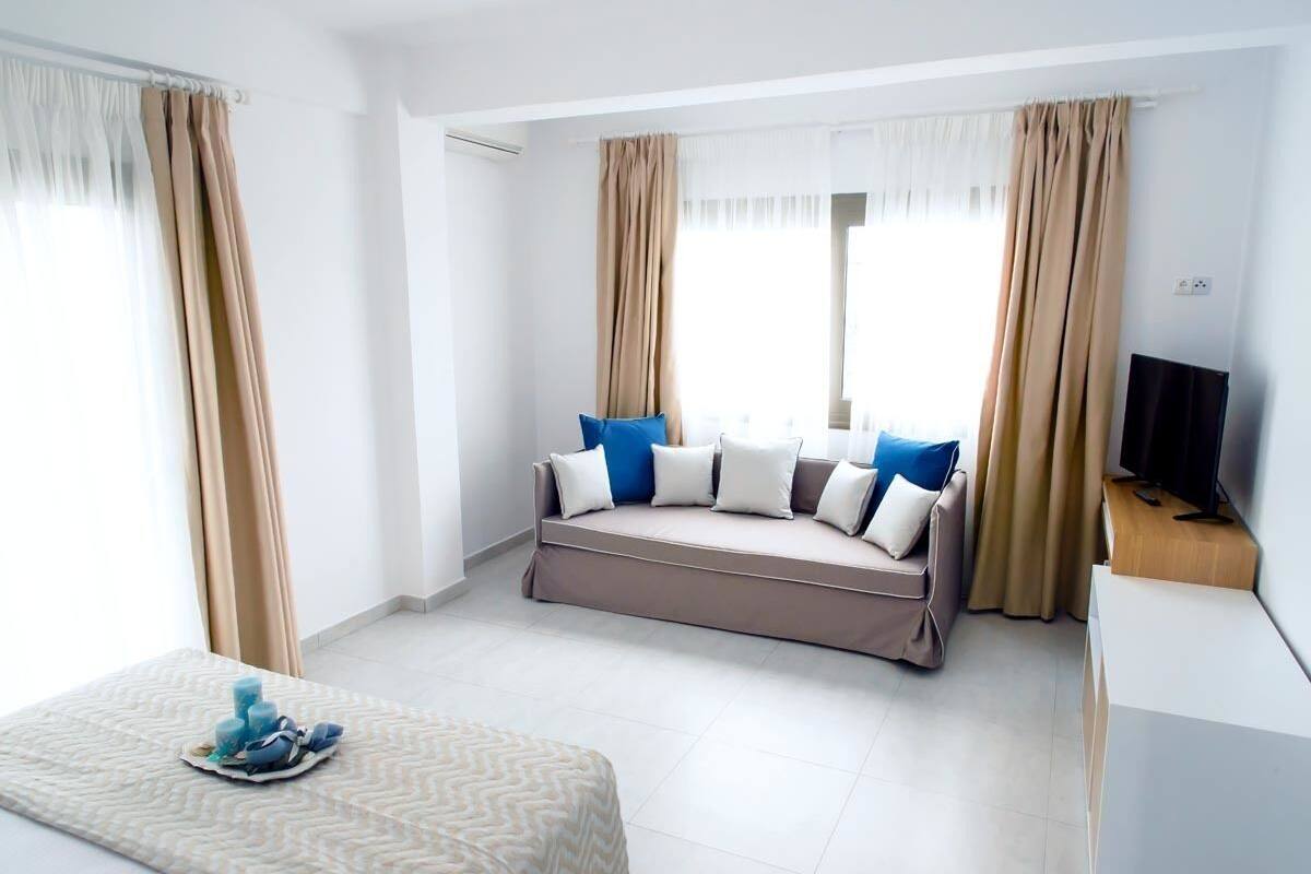 A modern hotel room with a sofa bed, a flat-screen TV, and a small table with a tray.