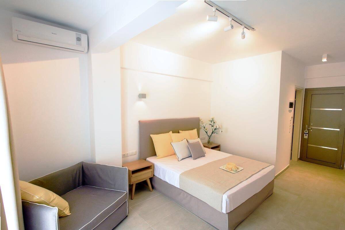A modern hotel room with a bed, bedside table, and a sofa.