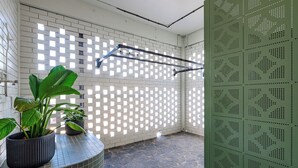 A tiled bathroom with a shower area, a towel rack, and potted plants. - The Queens Hotel Gladstone (Gladstone)