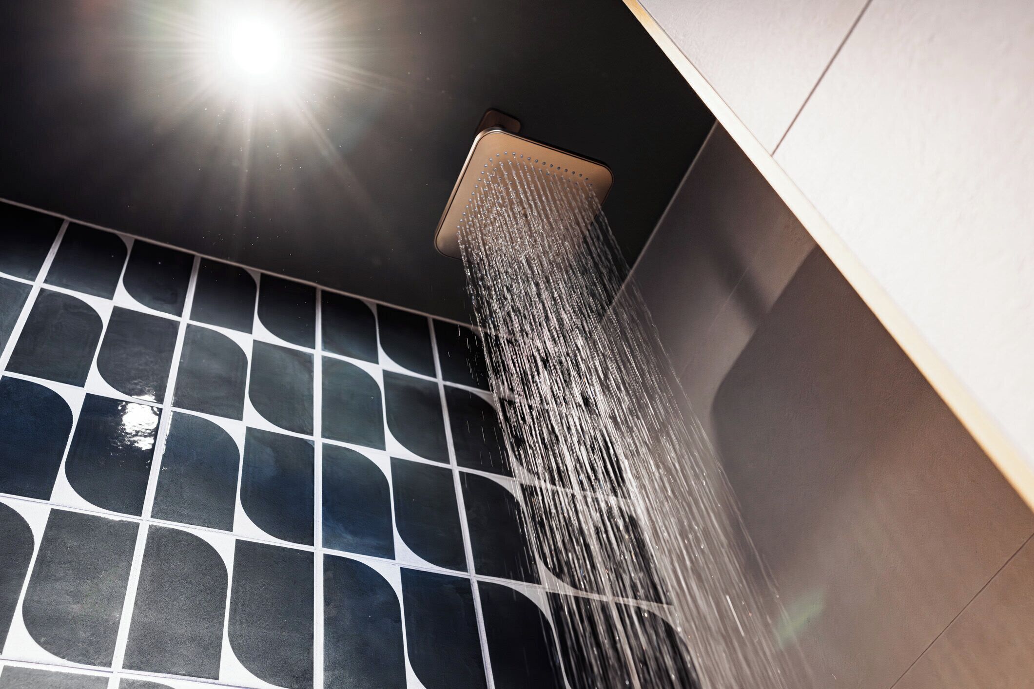 A shower with a square head and a tiled wall.