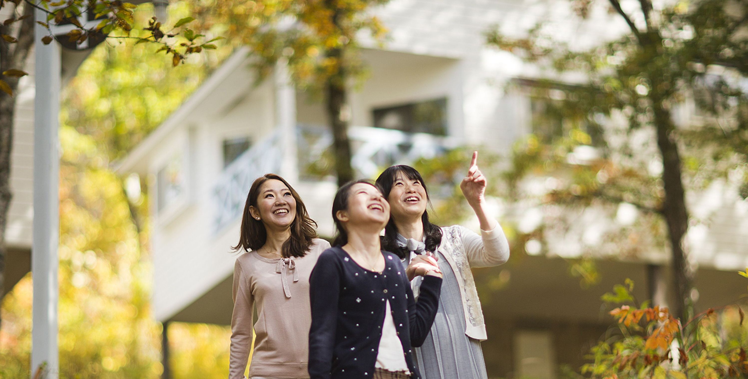 Three people standing outdoors with autumn foliage in the background.