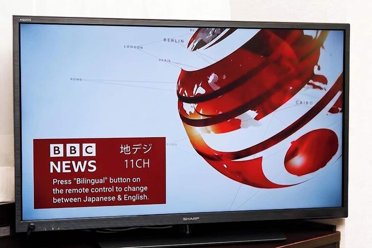 Un téléviseur diffusant les informations de BBC News 11CH, avec un motif abstrait rouge affiché à l’écran.