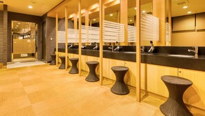 Un baño moderno con pisos de madera, encimeras negras y taburetes de mimbre.