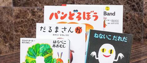 Una colección de libros infantiles con texto en japonés, un CD y un libro negro con una ilustración de un fantasma.