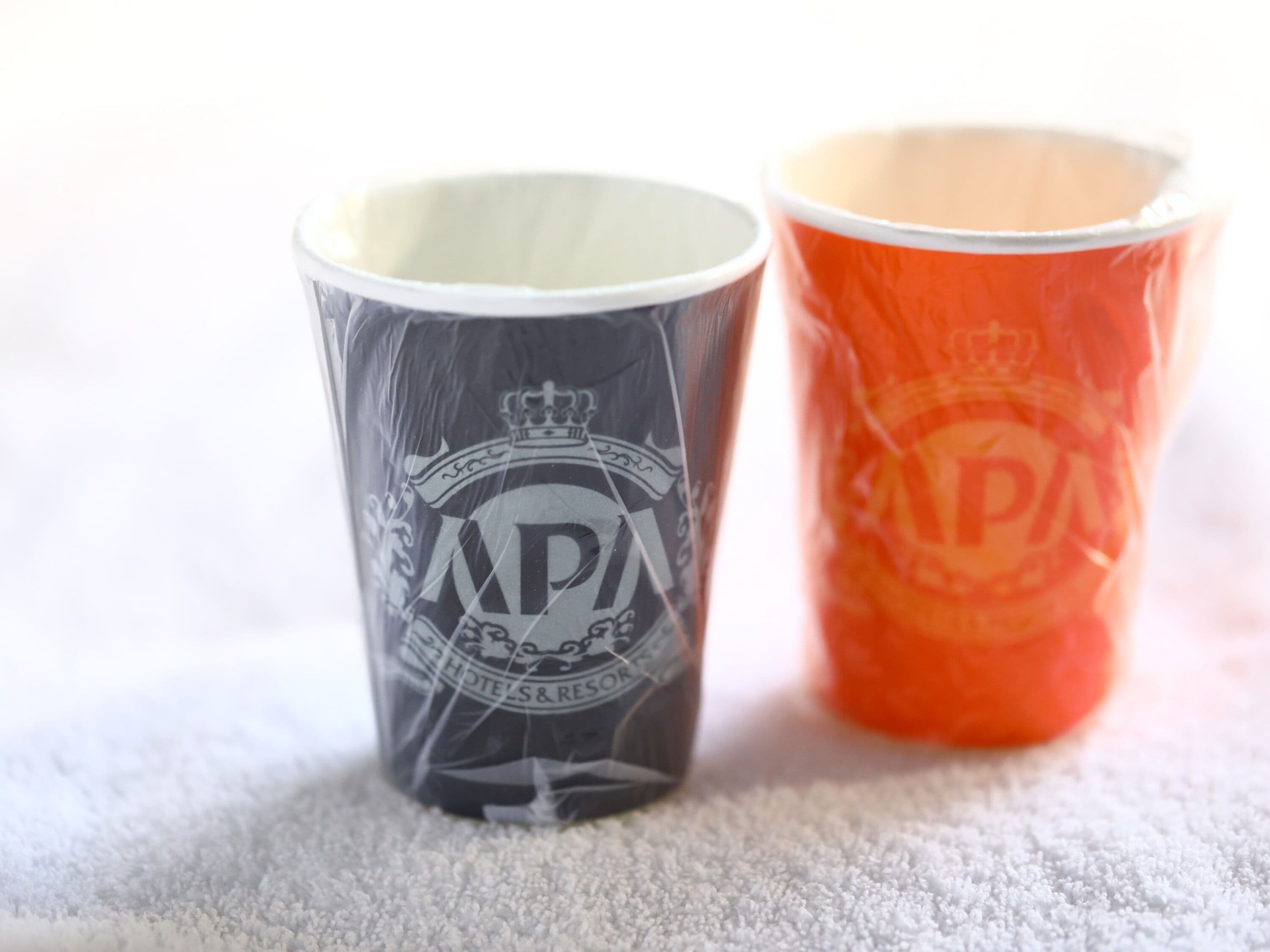 Two cups with printed designs, one with a crown and the other with a logo.