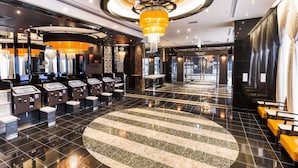 Un moderno vestíbulo de hotel con mostrador de recepción, un tapete circular grande y una araña.