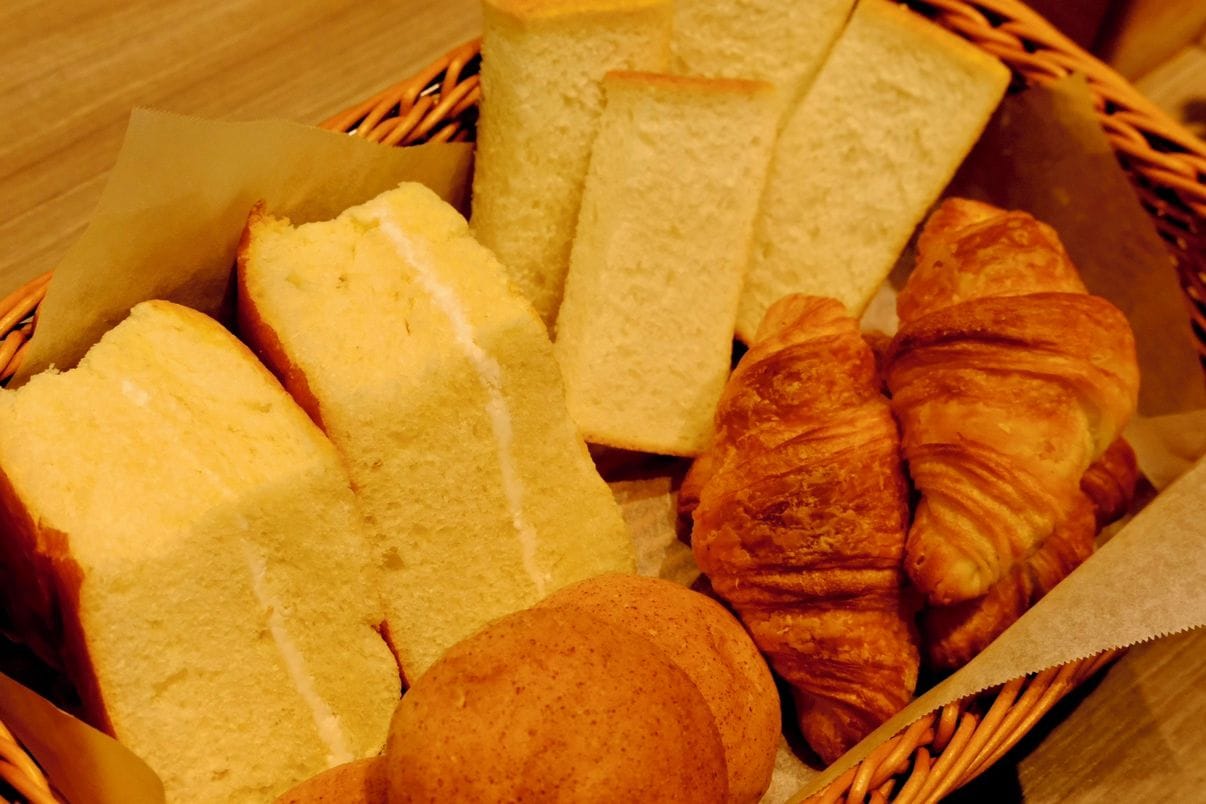 A basket containing slices of white bread and croissants.