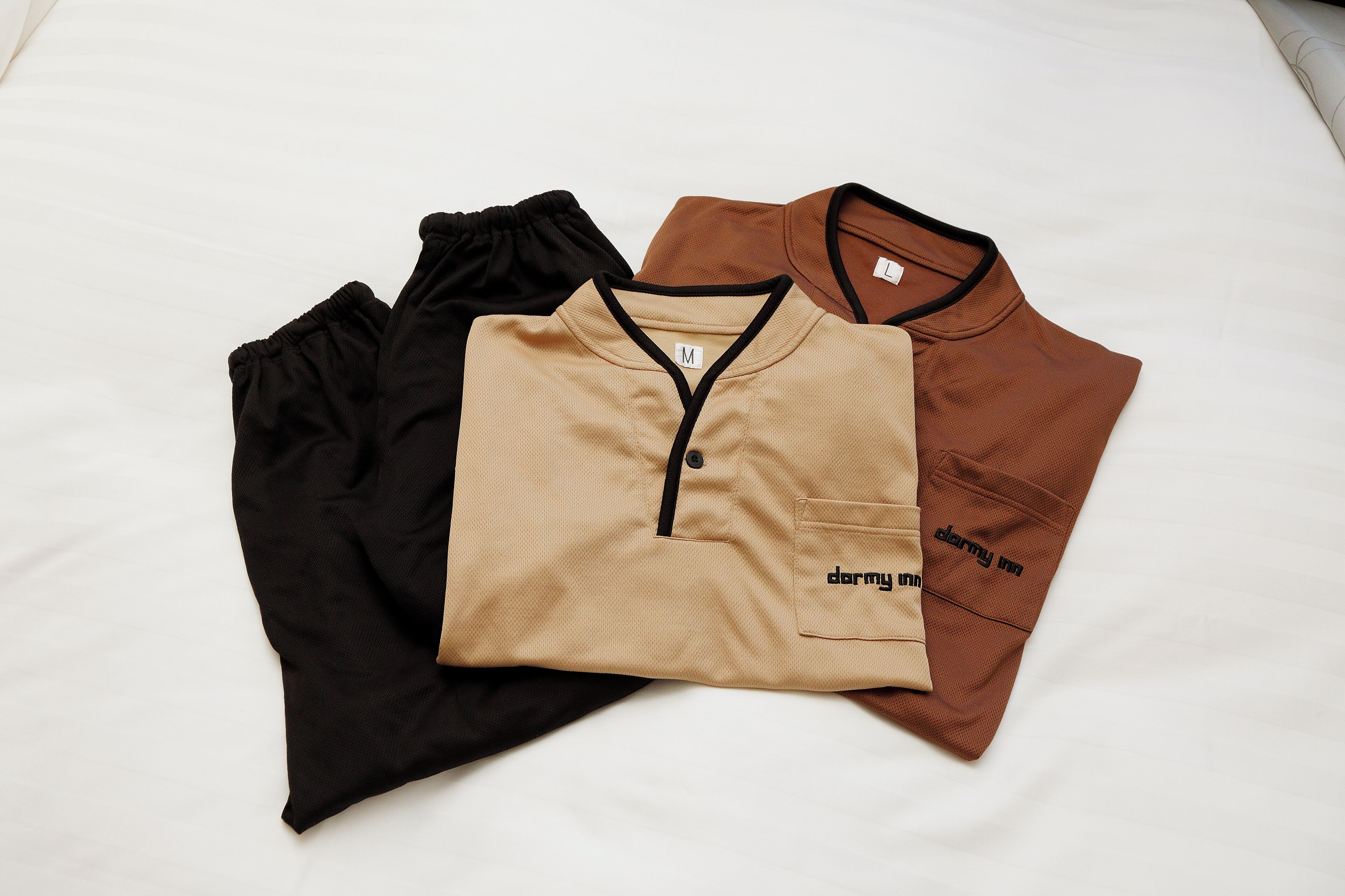 Three neatly folded shirts on a bed.
