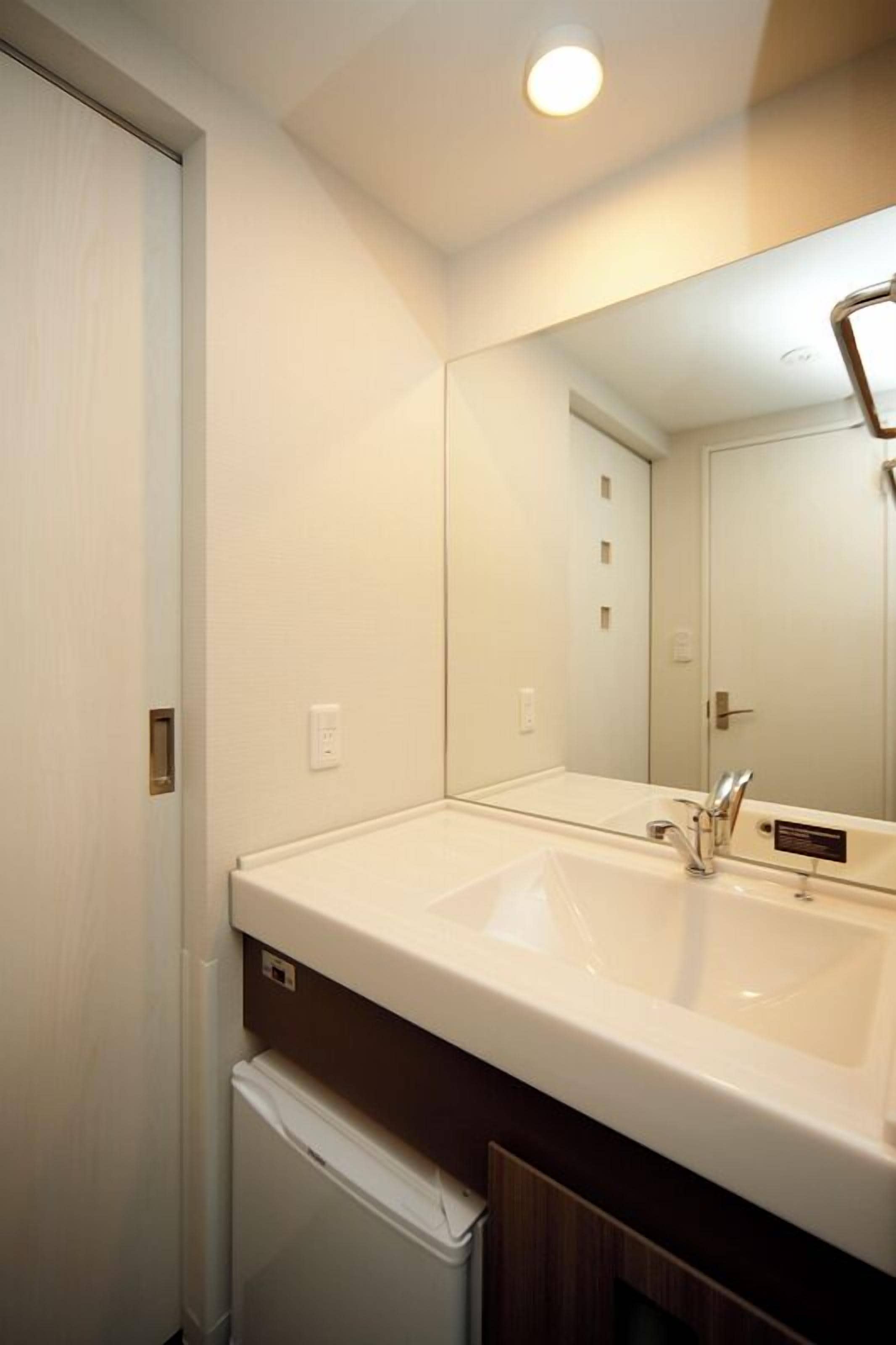 A bathroom with a white sink, a mirror, and a towel rack.