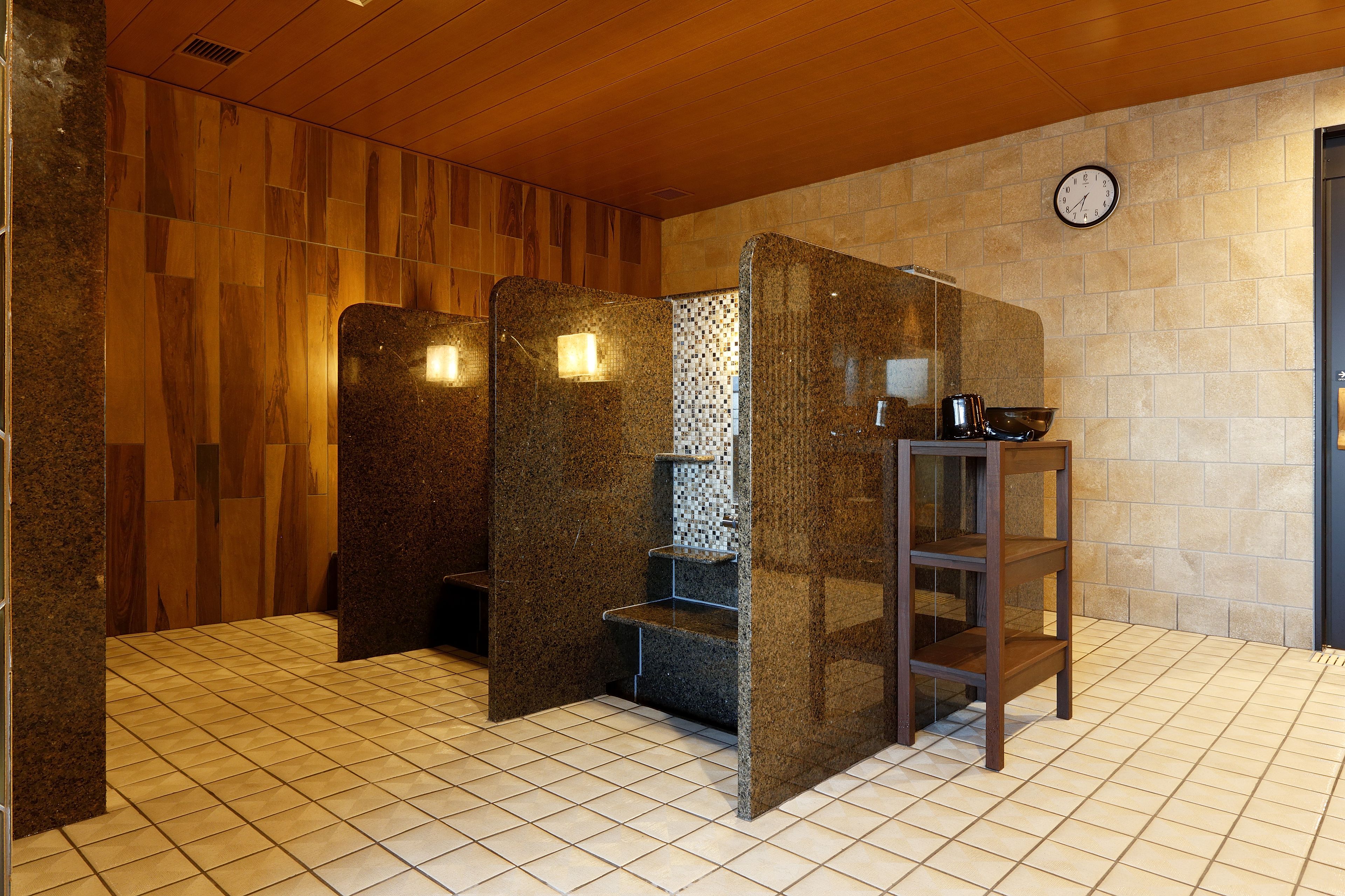 A sauna area with wooden walls, tiled floor, and a clock on the wall.