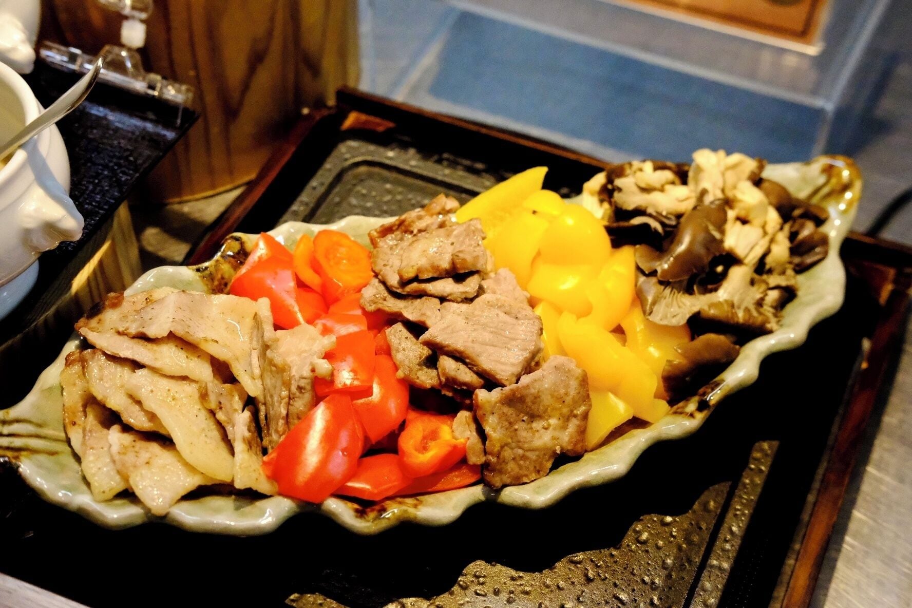 A plate with sliced meat, red bell peppers, and yellow bell peppers.