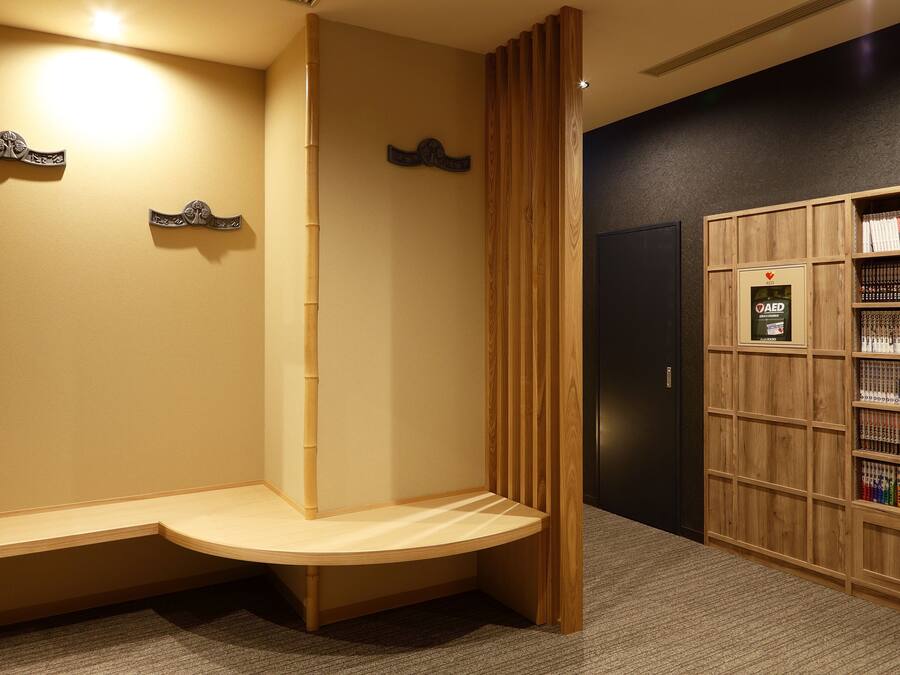 A reception area with a wooden bench, a bookshelf with books, and a wall-mounted AED sign.