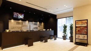 Un área de cocina moderna con encimera oscura, salpicadero de azulejos y una pantalla digital con el menú.
