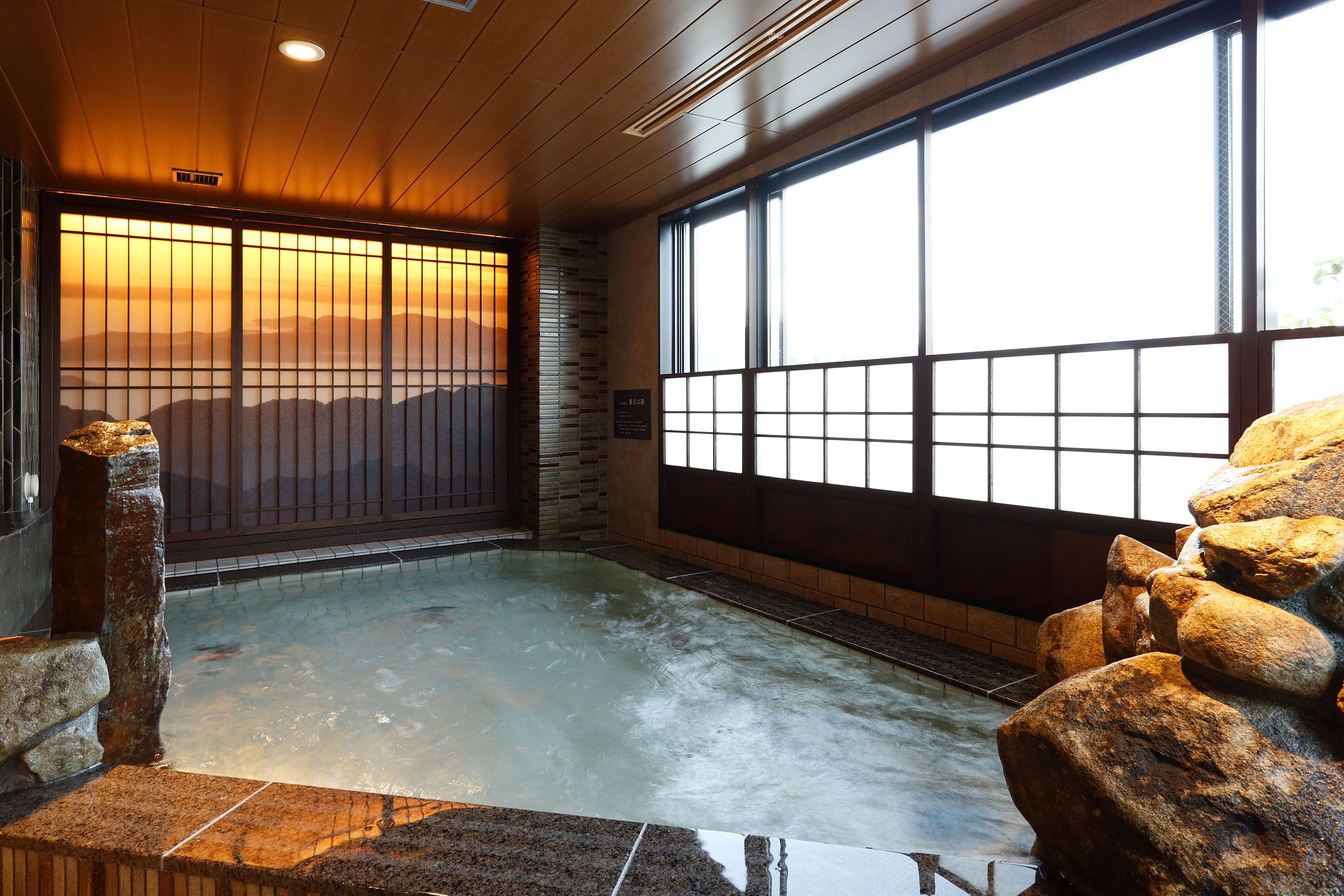 A traditional Japanese onsen with a view of the mountains through a shoji screen.