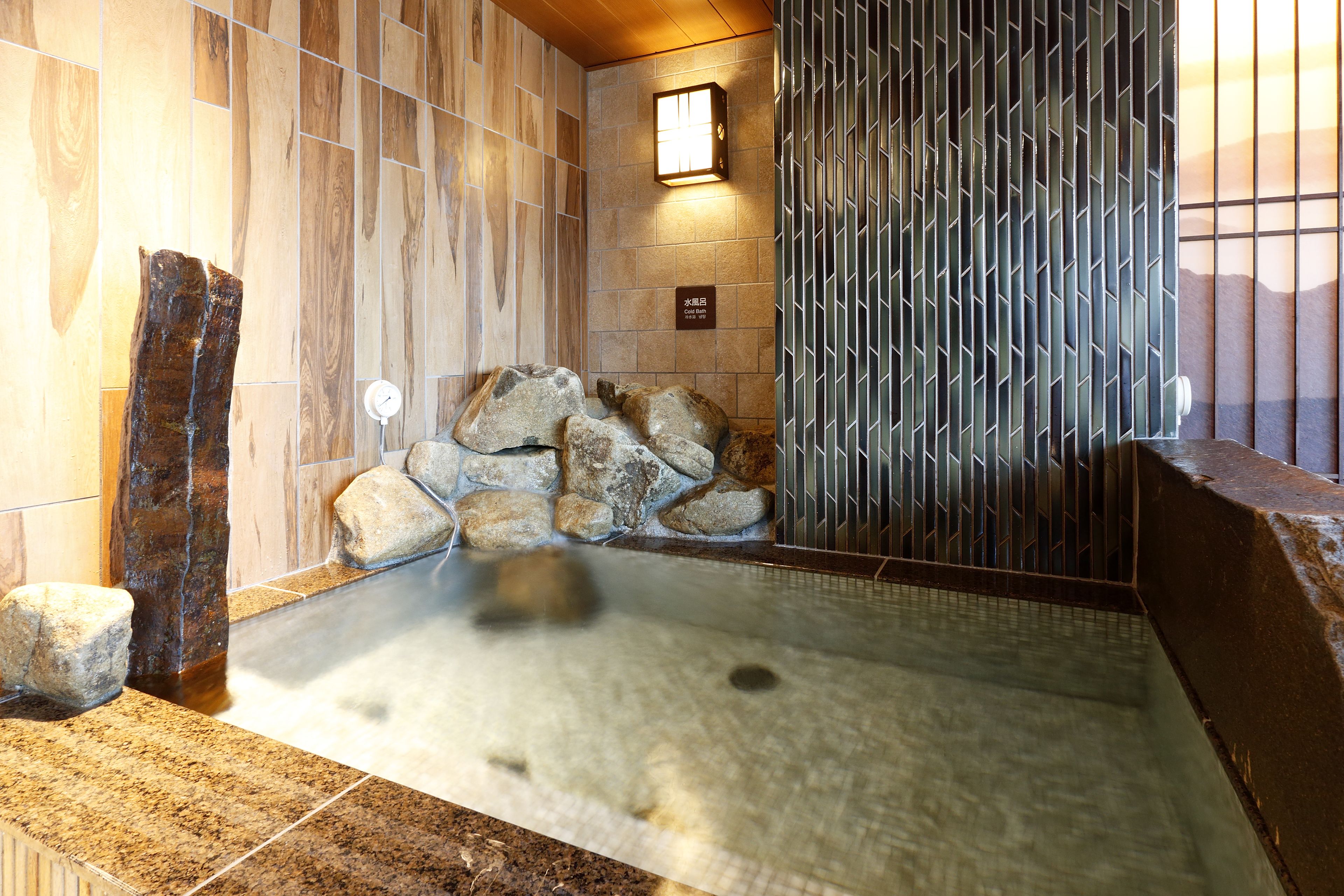 A stone hot tub with a wooden wall and a metal fence.