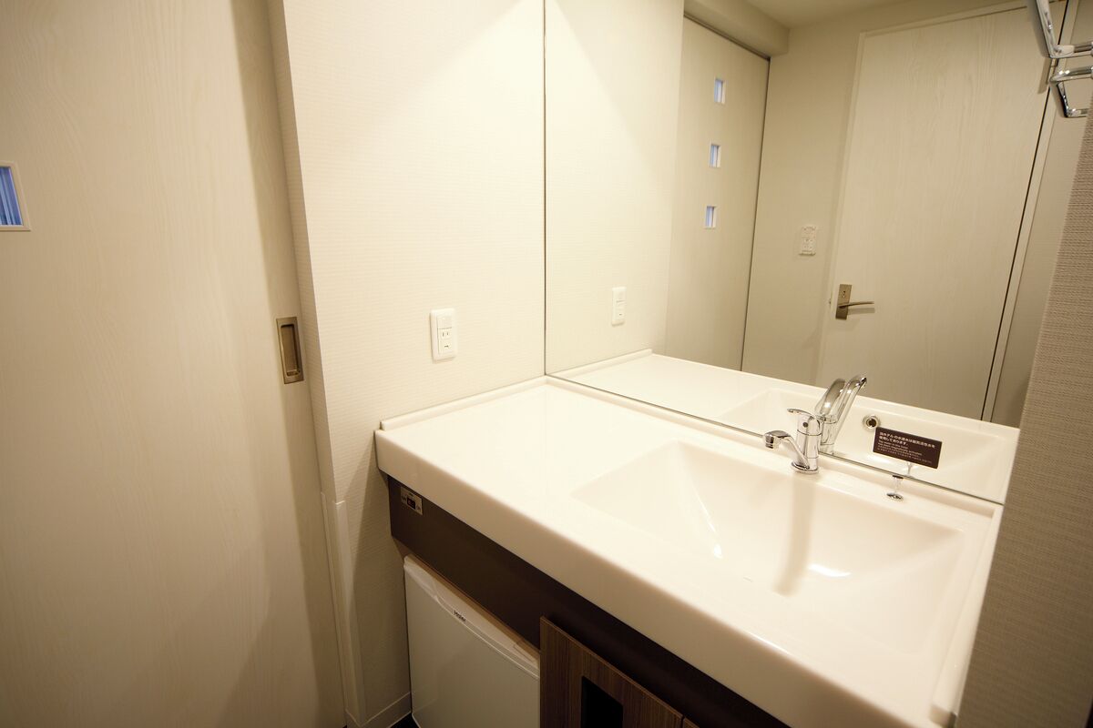 Un baño con un lavamanos blanco, un espejo y una puerta.