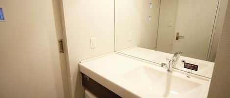 Un baño con un lavamanos blanco, un espejo y una puerta.