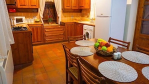 Une cuisine compacte dotée de meubles en bois, d’une cuisinière à gaz, d’un four à micro-ondes, d’un lave-linge et d’un réfrigérateur.